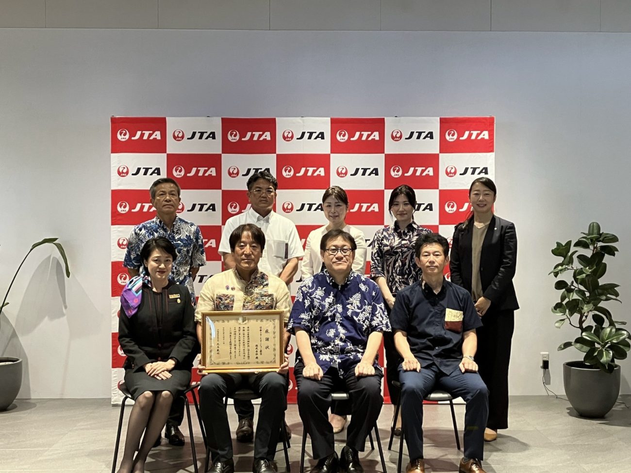 贈呈式で記念撮影に臨む、JTA代表取締役社長の野口望氏（前列中央左）や沖縄国税事務所 所長の児島範昭氏（同右）ら。