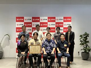贈呈式で記念撮影に臨む、JTA代表取締役社長の野口望氏（前列中央左）や沖縄国税事務所 所長の児島範昭氏（同右）ら。